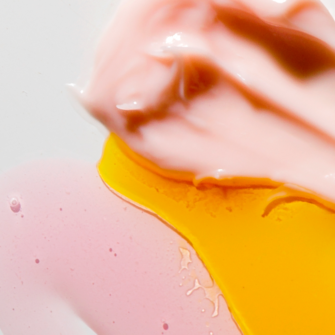 Swirls of pale pink, soft yellow, and light peach creams blend together on a smooth surface, creating an abstract, colorful texture.