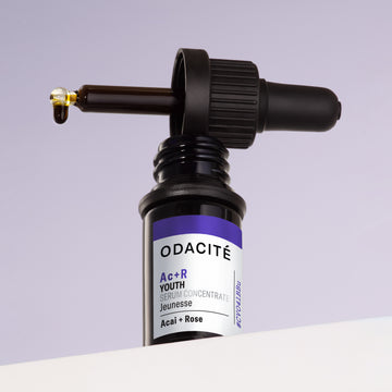 Dropper held above Odacite Youth Acai + Rose Ac+R Serum Concentrate, set against a light purple background.