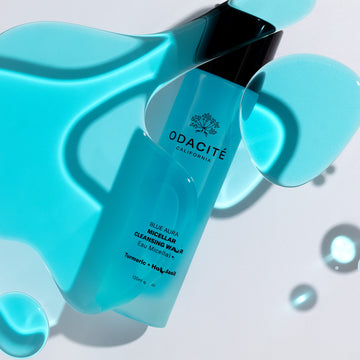 Odacité Blue Aura Turmeric + Holy Basil Micellar Cleansing Water with turquoise liquid in a clear bottle on a white background.
