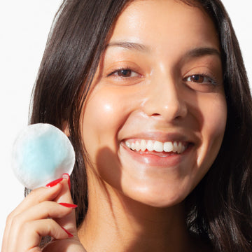 Woman with clear skin applies Odacité Blue Aura Turmeric + Holy Basil Micellar Cleansing Water during her skincare routine.