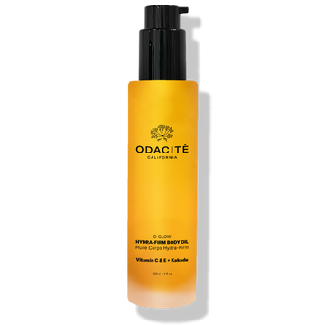 Odacité C-Glow Hydra-Firm Body Oil with Vitamin C & E + Kakadu in a yellow bottle with black pump, set against a white background.