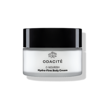 Odacité C-Nourish Hydra-Firm Body Cream with Vitamin C & E + Kakadu Plum in a jar with a black lid on a light background.