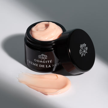 Odacité Crème de la Nuit Night Cream jar with the lid off, showing a swirl of cream on a white background.