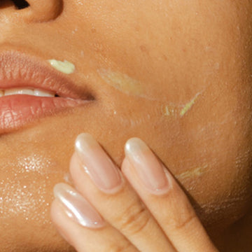 Person applying Odacité’s Derm-Restore Super Serum • Edelweiss Extrême® from a dropper to their cheek in a close-up view.