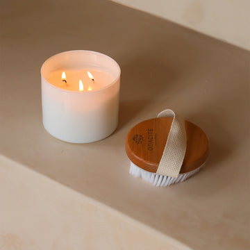 The Odacité Dry Spa Brush with natural bristles lies on a smooth beige surface.