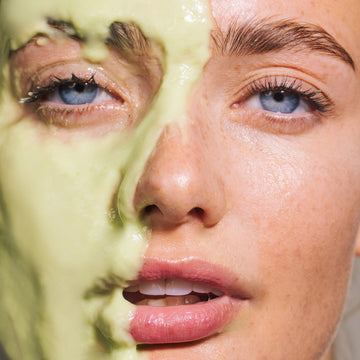 Close-up of a woman’s face with Odacité Green Smoothie® Crème on one side, showing blue eyes and hydrated skin texture.