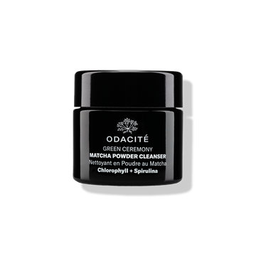 Odacité Green Ceremony Cleanser with chlorophyll and spirulina matcha powder in a black jar on a white background.