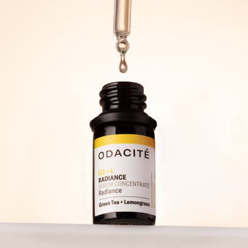 A dropper is held above an open Odacite Radiance Green Tea + Lemongrass Gt+L Serum Concentrate glass bottle.