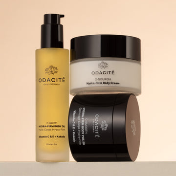 Odacité Hydra-Firm Full Body Routine body oil, cream, and polish displayed on a beige background.