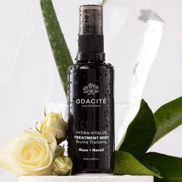 Odacité Hydra-Vitalize • Rose + Neroli • Treatment Mist bottle with a white rose, aloe vera leaf, and green leaves in the background.