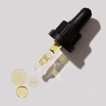 Odacite Jo+L Clogged Pores Jojoba + Lavender Serum Concentrate dropper and three serum drops on a light gray background.