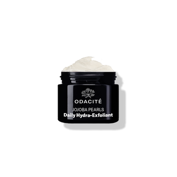 Open black jar labeled Odacité Jojoba Pearls • White + Rooibos Tea Daily Hydra-Exfoliant with gentle exfoliant visible inside.