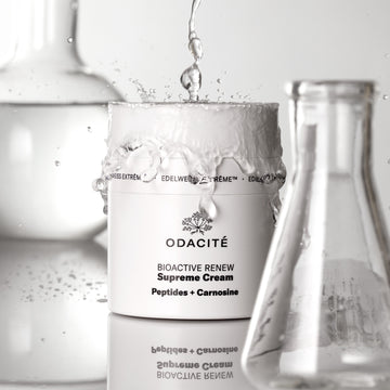 Odacité Bioactive Renew Supreme Cream • Edelweiss Extrême® + Peptides & Carnosine jar with lab beakers and water splashes nearby.
