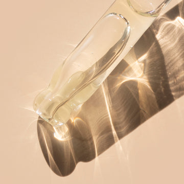 Odacite Pa+G Serum Concentrate with papaya oil in a glass bottle on a beige surface with soft shadows and reflections.
