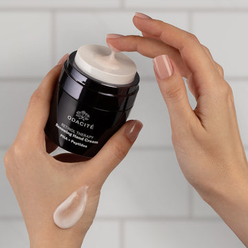 A person applies Odacité Vitamin C & Retinol Targeted Body Essentials from a pump bottle onto the back of their hand.