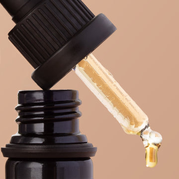Odacite Ro+Y Deep Wrinkles Serum dropper above its dark bottle on a beige background.