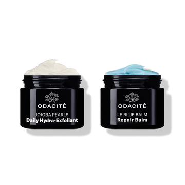 Odacité Smooth & Soothe Duo with two open black jars: daily exfoliant (white cream) and repair balm (blue cream).
