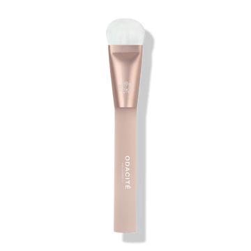 Odacité Universal Brush with white bristles and a rose gold and blush pink handle, shown on a plain background.
