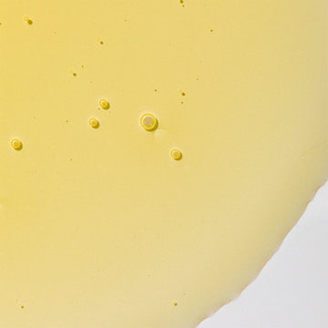 Bright yellow Odacite Ba+S Eye Contour Rollerball serum with small bubbles visible inside the clear tube.