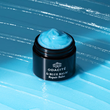 Odacite le Blue Balm jar, labeled Blue Chamomile + Shea Butter, sits on a blue textured surface.
