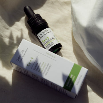 Odacite Ca+C Sensitive Skin Camelina + Chamomile Serum bottle and box on white fabric in sunlight.