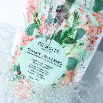 Odacite Relax & Recenter Bath Set with Himalayan Crystal Salt and herbs, in clear water with visible splashes.