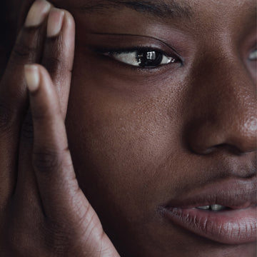 Hand rests on smooth, even-toned cheek, highlighting skin after use of Odacité Le Complex 46 Revitalizing Bioactive Serum.