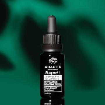 Black Odacité Le Complex 46 Revitalizing Bioactive Serum bottle with dropper on a green and black background.
