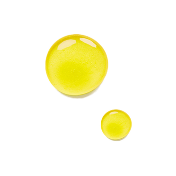 Two yellow drops of Odacite Ro+Y Deep Wrinkles Rosehip + Ylang-Ylang Serum Concentrate on a plain background.